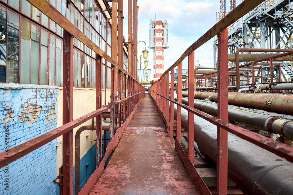 Industry highway walkway platform with grate and handrail on petrochemical plant factory with lighting masts and explosion-proof fireproof design rusty retro style lanterns and urea tower granulator. Industry highway walkway platform with grate and handrail on petrochemical plant factory with lighting masts and explosion-proof fireproof design rusty retro style lanterns and urea tower granulator.