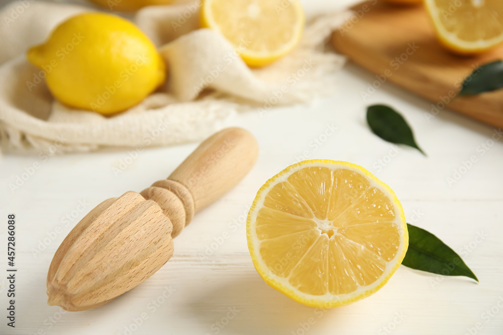 Wooden citrus reamer and halved fresh lemon on white table, closeup Wooden citrus reamer and halved fresh lemon on white table, closeup