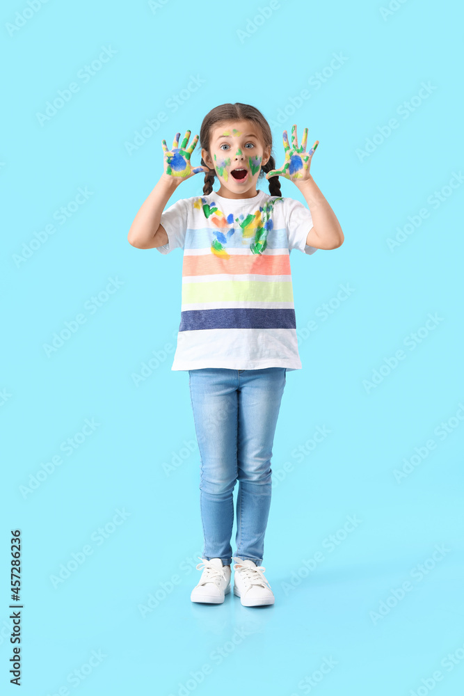 Surprised little girl in paint on blue background Surprised little girl in paint on blue background