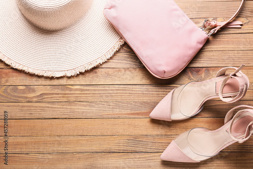 Stylish shoes, handbag and hat on wooden background
