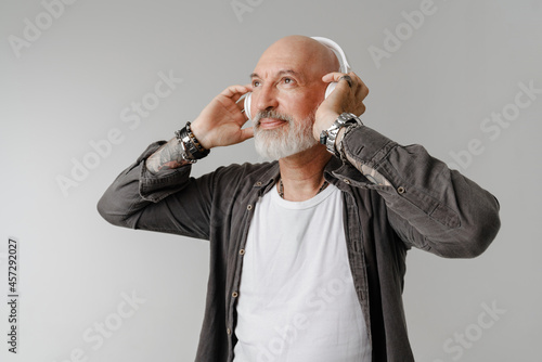 Bald bearded european man listening music with headphones