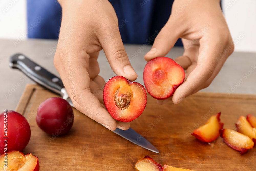 Woman with cut ripe plums at table, closeup Woman with cut ripe plums at table, closeup