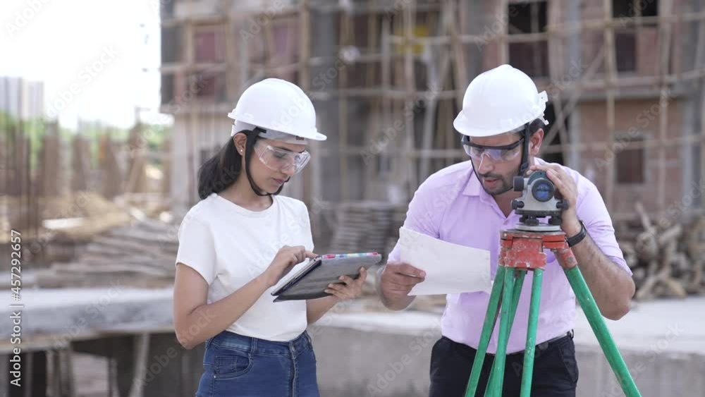 Two Indian man and woman Civil Engineers work at Construction Site outdoor.Two Asian worker checking work details on construction site.two civil engineers doing a survey on a construction site. Two Indian man and woman Civil Engineers work at Construction Site outdoor.Two Asian worker checking work details on construction site.two civil engineers doing a survey on a construction site.