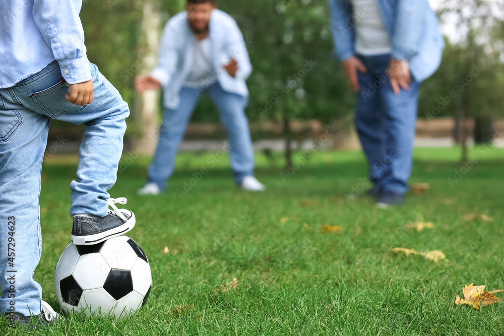 Man, his little son and father playing football in park Man, his little son and father playing football in park