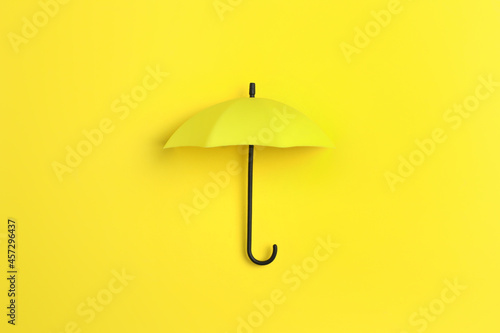 Bright toy umbrella on yellow background, top view