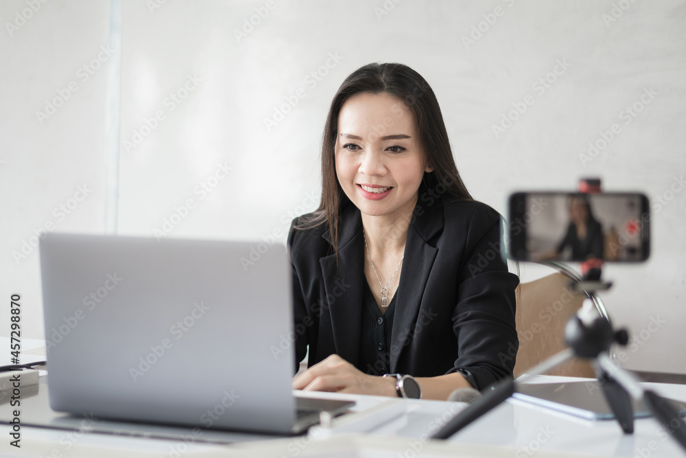 Adult Asian female college teacher teaching online via video conference meeting to students at home. Smiling Asian female tutor having a video call with students