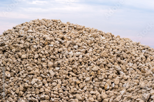 A large pile of sand-colored rubble against a gray-blue sky. Background