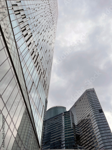 Facade of modern skyscraper with glass walls. From below of contemporary tall skyscraper with glass walls against cloudy sky in downtown