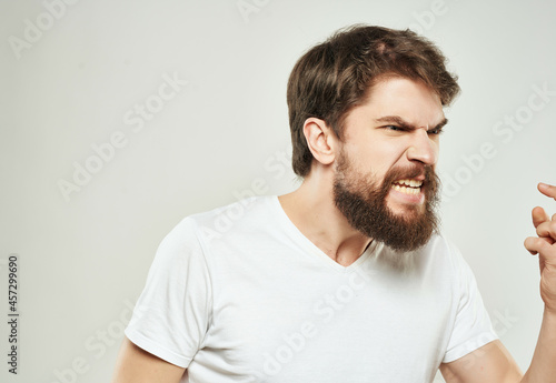 bearded man in a white t-shirt hand gestures anger close-up