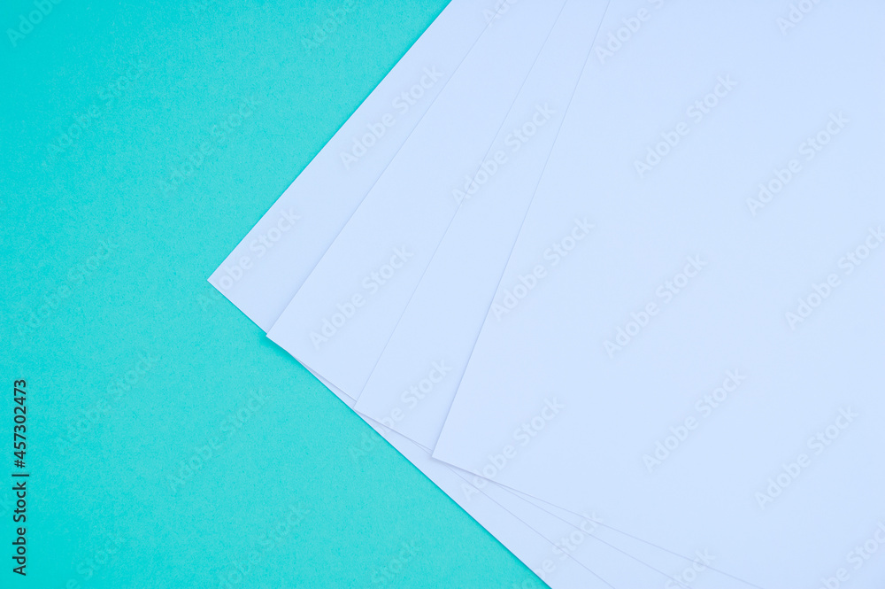 Four white sheets of paper  turquoise background. Stationery.