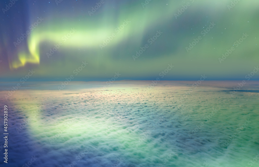 Northern lights or Aurora borealis in the sky over the clouds 