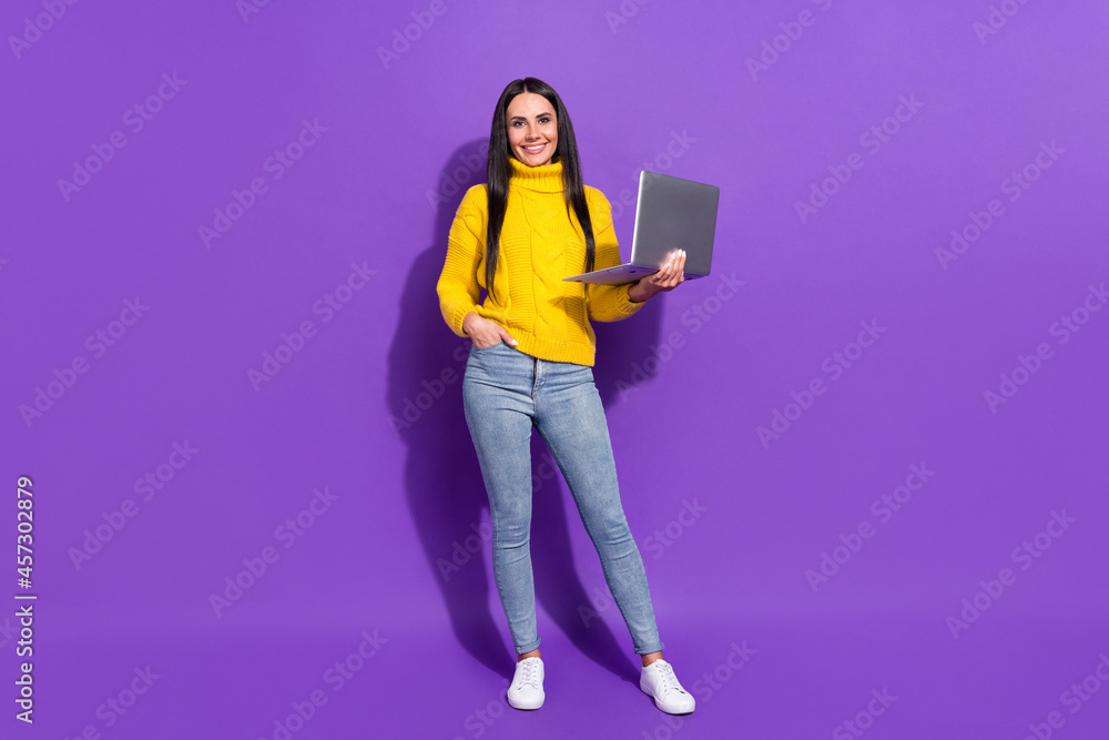 Full size portrait of charming cheerful girl hold laptop look camera beaming smile isolated on purple color background Full size portrait of charming cheerful girl hold laptop look camera beaming smile isolated on purple color background