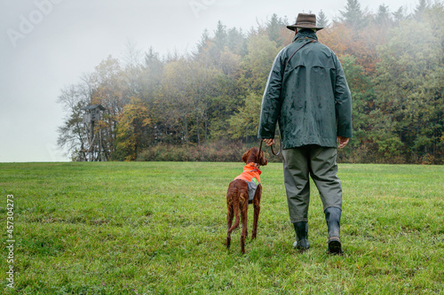 On a foggy, rainy autumn day a hunter with his dog make a stalking through the hunting area to the big Hunting Pulpit which stands at the edge of the forest.