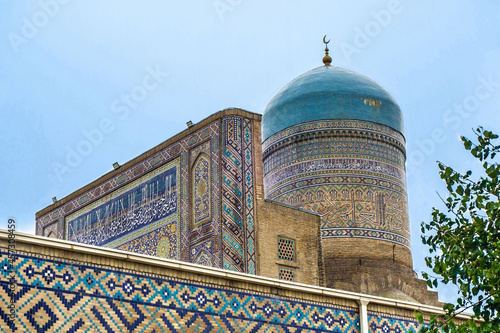Dome, iwan and part of wall of Nadir Divan-Begi madrasa in Samarkand, Uzbekistan. Elements  decorated with traditional patterns and ornaments. Inscriptions on  building are quotes of suras from Koran photo