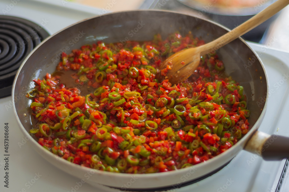 finely chopped tomatoes and peppers are sautéed in a pan. finely chopped tomatoes and peppers are sautéed in a pan.