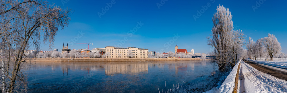 Panoramic view over Magdeburg historical downtown in Winter with icy trees and snow during sunrise in the morning with warm illumination and blue sky, Germany.