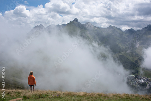 girl looking out over the mountains and clouds with a village in the valley