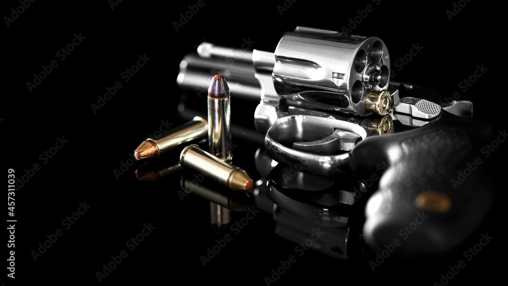 Chrome revolver with tilted drum and ammunition on black mirror background. Chrome revolver with tilted drum and ammunition on black mirror background.
