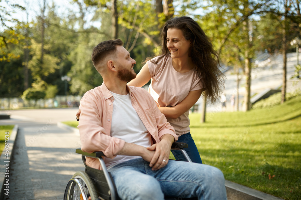 Young couple with wheelchair walking in the park