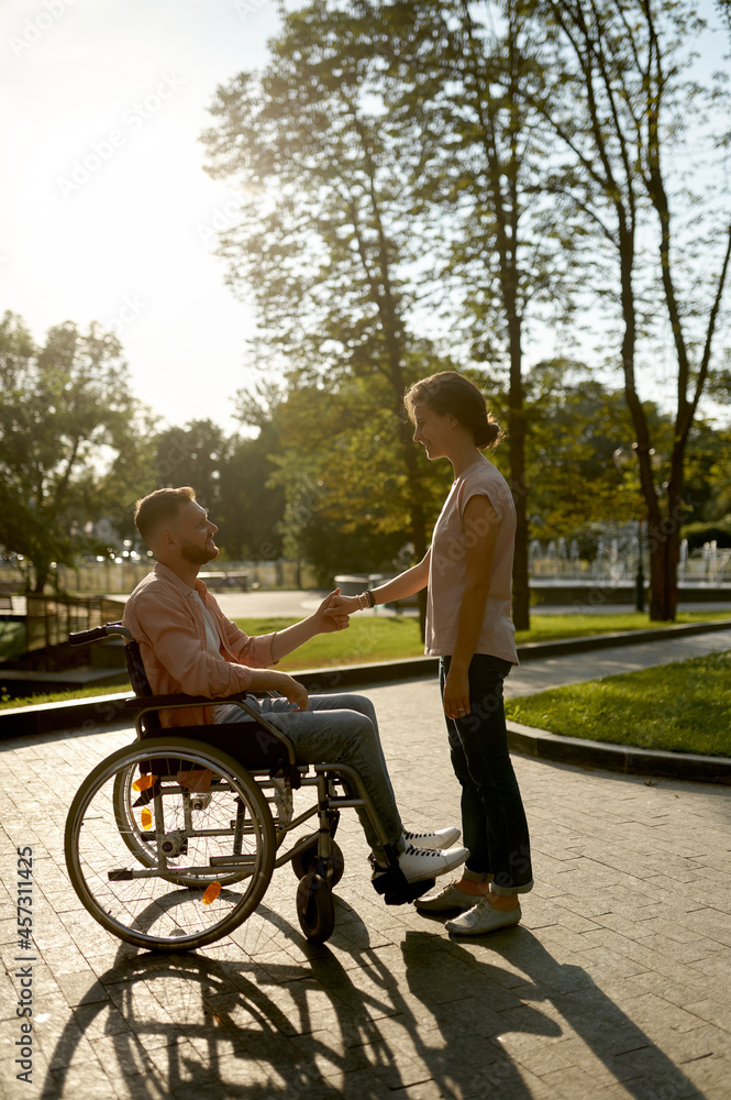 Family couple with wheelchair walking in park Family couple with wheelchair walking in park
