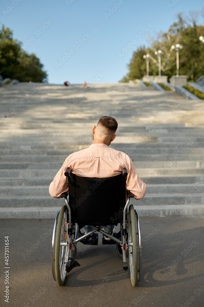 Man in wheelchair at the stairs, back view