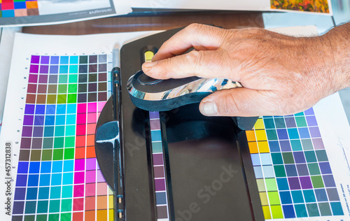 Technician uses a spectrocolorimeter to read patches with various colors for color management related to creating an icc color profile for the printer photo
