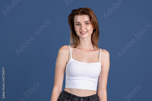 Smiling young girl looking at camera isolated on old navy color studio background. Concept of human emotions, facial expression, natural beauty, appearance, youth