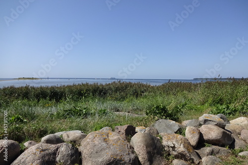 Landscape with big stones in the front. Green grass by seaside. Clear blue sky on a sunny summer day. Tallinn, Estonia, Europe, August 2021