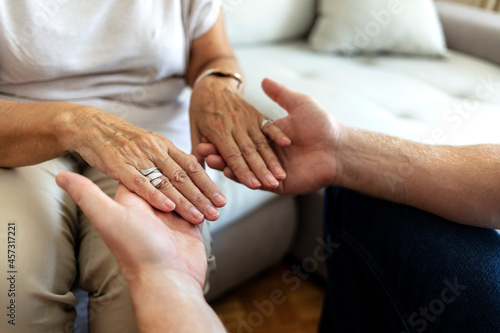 A cropped shot of a man holding a loved one's hand in support. Grandson gives grandmother his hands. Shot of an unrecognizable senior female holding hands with her son while sitting on a couch at home
