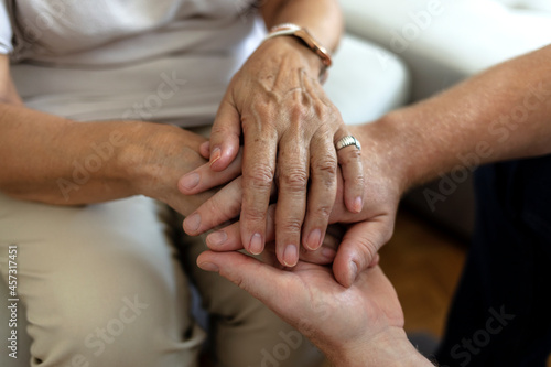 A cropped shot of a man holding a loved one's hand in support. Grandson gives grandmother his hands. Shot of an unrecognizable senior female holding hands with her son while sitting on a couch at home