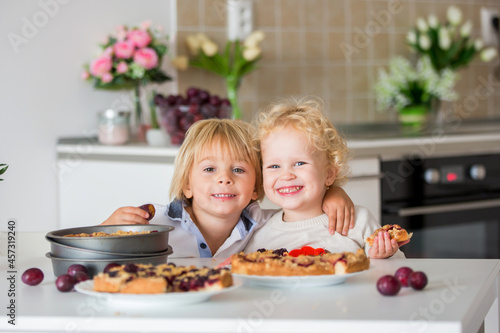 Cute little toddler child, eating homemade plum pie at home