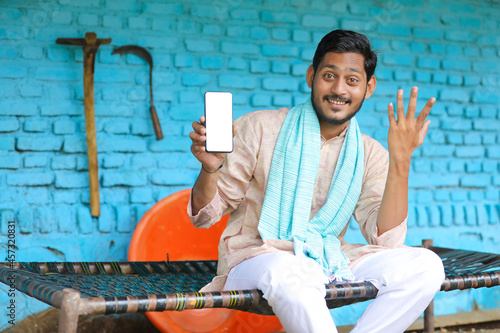 technology concept : Young indian farmer showing smartphone at his home photo