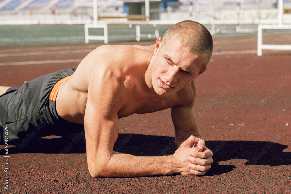 Young man doing plank exercises at stadium, abdominal muscles and cortex training Young man doing plank exercises at stadium, abdominal muscles and cortex training