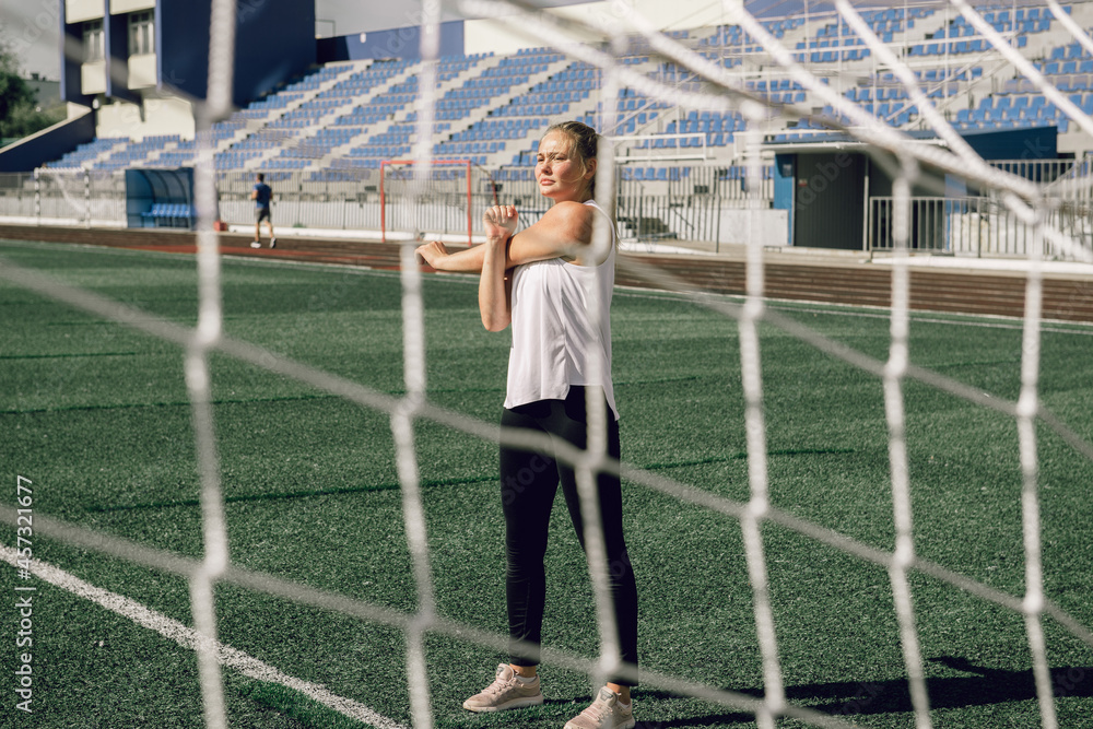 Young woman doing stretching sport exercises at stadium workout