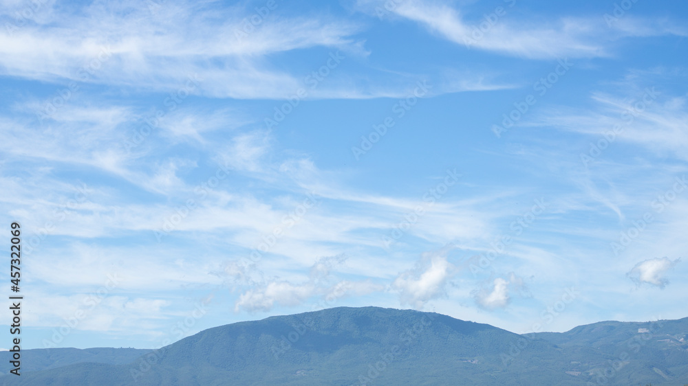 green grass landscape with mountains and blue sky with white clouds