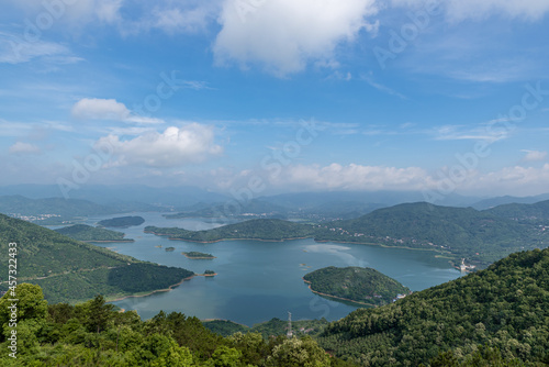 A lake surrounded by forests under blue sky and white clouds