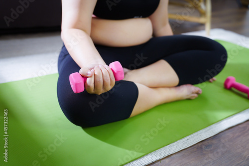 Overweight woman exercising for weight loss. exercise with dumbbells in stretching positions at home in the living room Cheerful Fat woman diet healthy lifestyle concept.