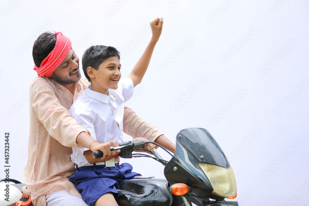 Young indian farmer dropping his child to school on bike. Young indian farmer dropping his child to school on bike.