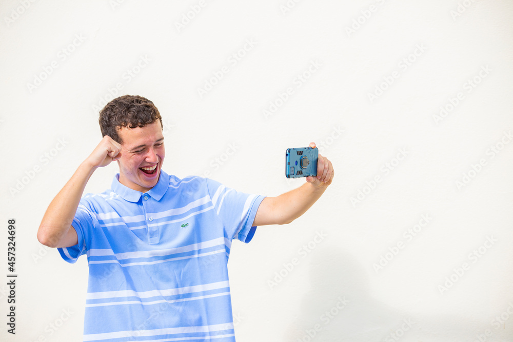 chico joven sonriente celebración en videollamada con teléfono móvil fondo amarillo chico joven sonriente celebración en videollamada con teléfono móvil fondo amarillo