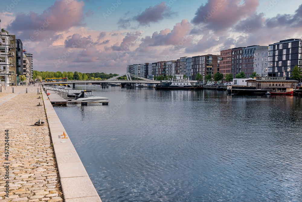 Beautiful canals of Copenhagen, the capital of Denmark. Magical summer view of Copenhagen city narrow streets, buildings, pedestrian bridges and boats down the canals.