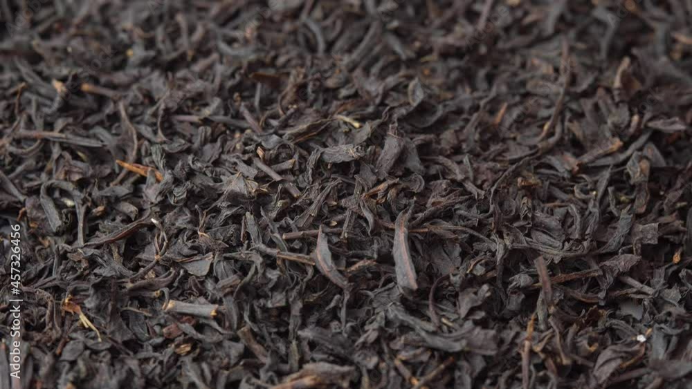 Background for a cafe or restaurant, black loose leaf tea sprinkled on a plate and spinning close up, tea advertising Background for a cafe or restaurant, black loose leaf tea sprinkled on a plate and spinning close up, tea advertising