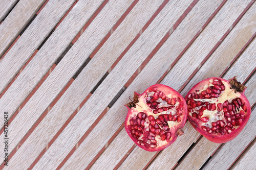 Overhead of open in half pomegranate on a wooden table shot with natural light. Copy space.