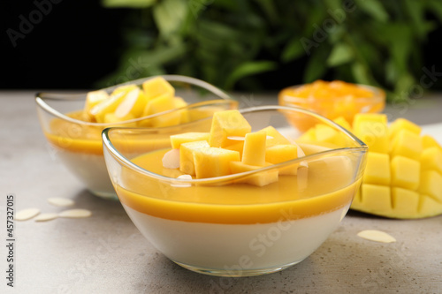 Delicious panna cotta with mango coulis and fresh fruit pieces on grey table photo