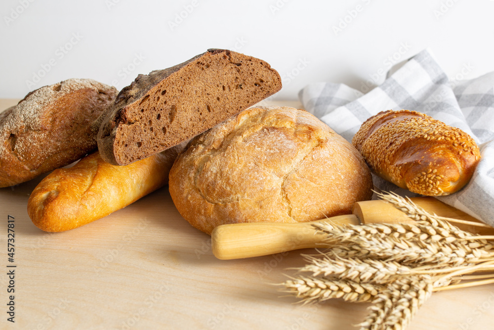 assortment of bread, bread and wheat on the table, loaves of assorted freshly baked bread on a stone background