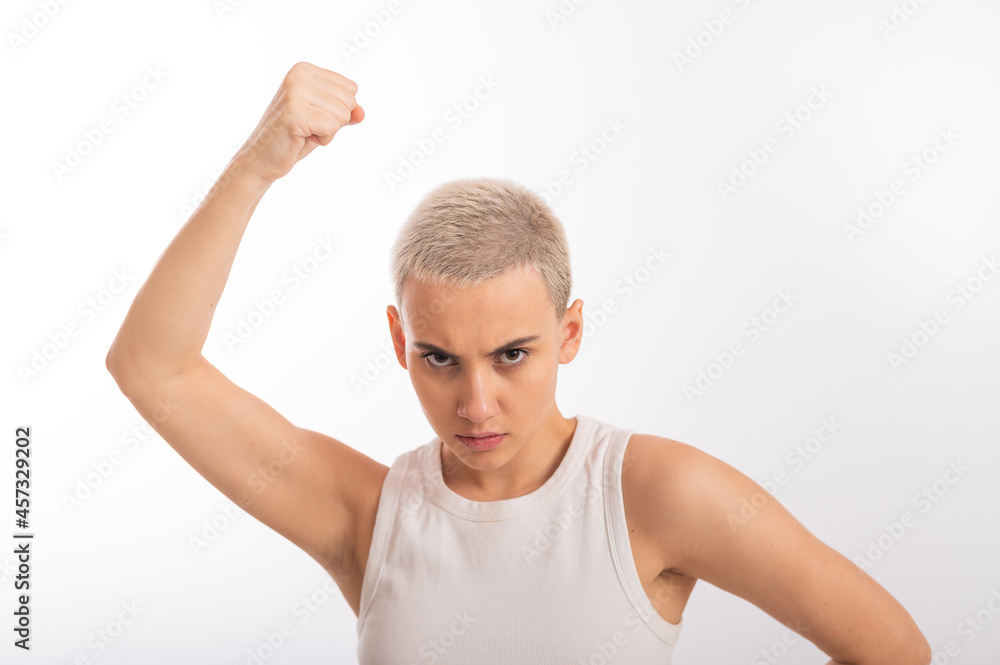Young caucasian woman holding her fist up on a white background. A girl with short hair is fighting for rights Young caucasian woman holding her fist up on a white background. A girl with short hair is fighting for rights