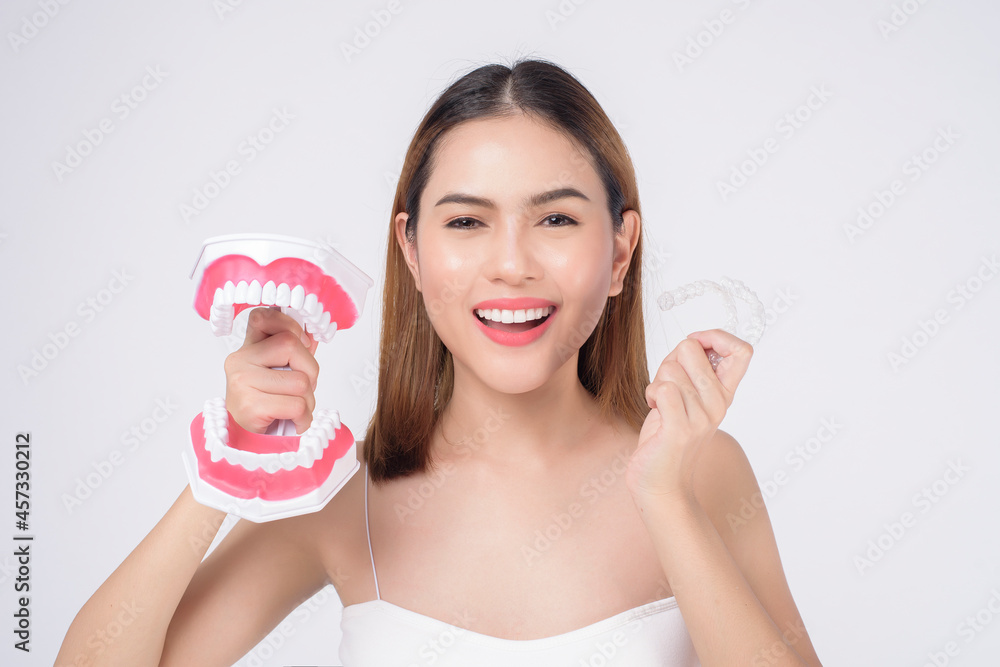 Young smiling woman holding invisalign braces in studio, dental healthcare and Orthodontic concept Young smiling woman holding invisalign braces in studio, dental healthcare and Orthodontic concept