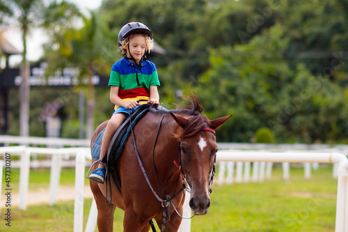 Kids ride horse. Child on pony. Horseback riding.