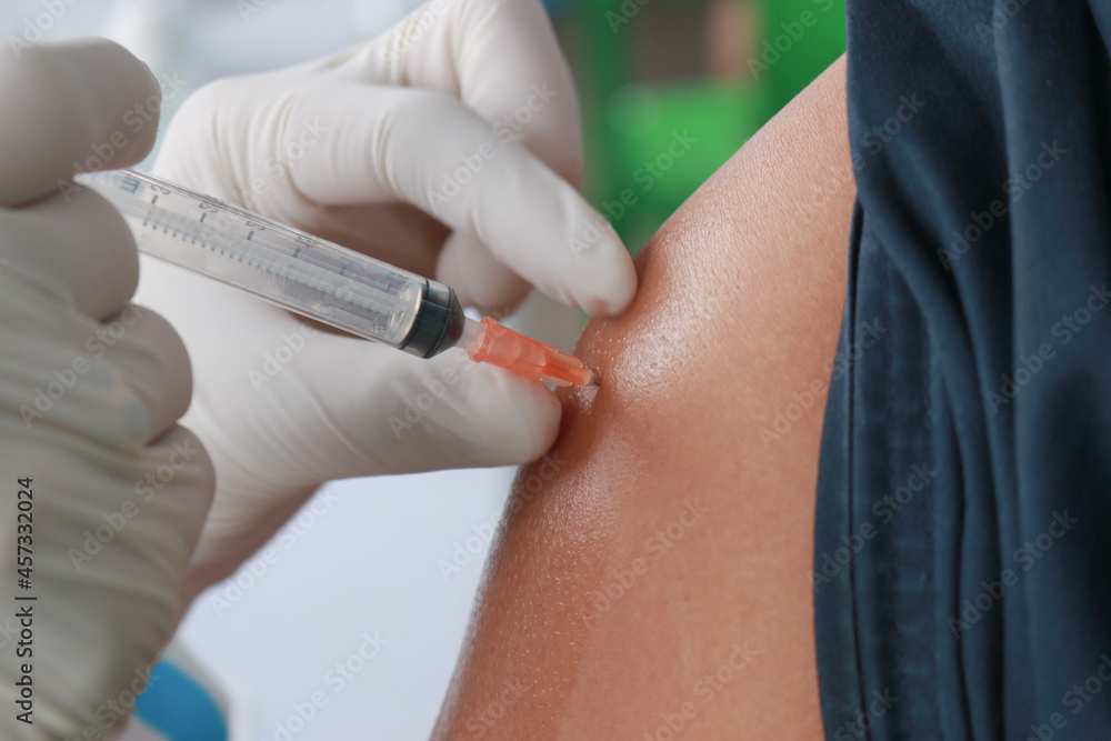 Close up Doctor injecting COVID-19 vaccine on a person's shoulder, Vaccination, immunization, disease prevention concept Close up Doctor injecting COVID-19 vaccine on a person's shoulder, Vaccination, immunization, disease prevention concept