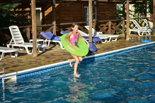 Fototapeta Naklejka Na Ścianę i Meble -  girl with a circle jumps with a run into the pool in the evening