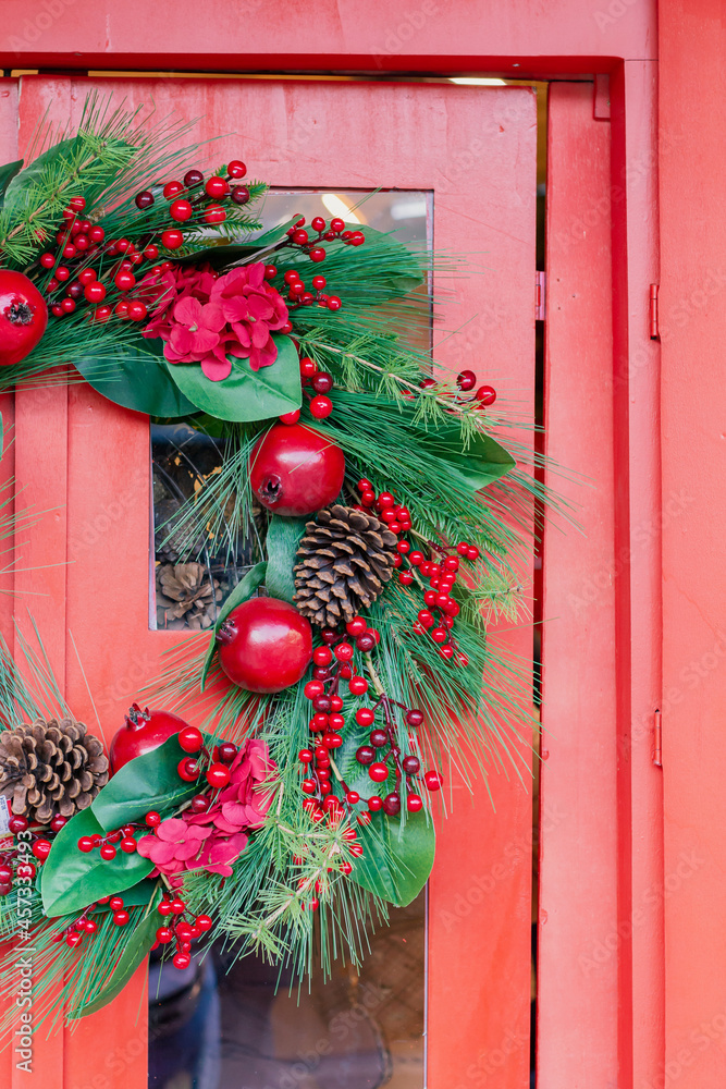 Christmas new year wreath with red berries and cones on a red wooden door, Christmas holiday decoration concept Christmas new year wreath with red berries and cones on a red wooden door, Christmas holiday decoration concept